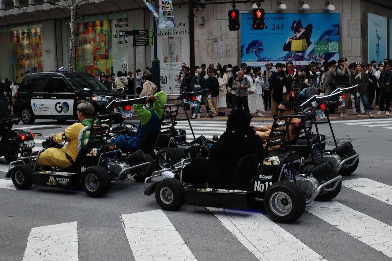 street scene with modified go-karts and spectators at an event