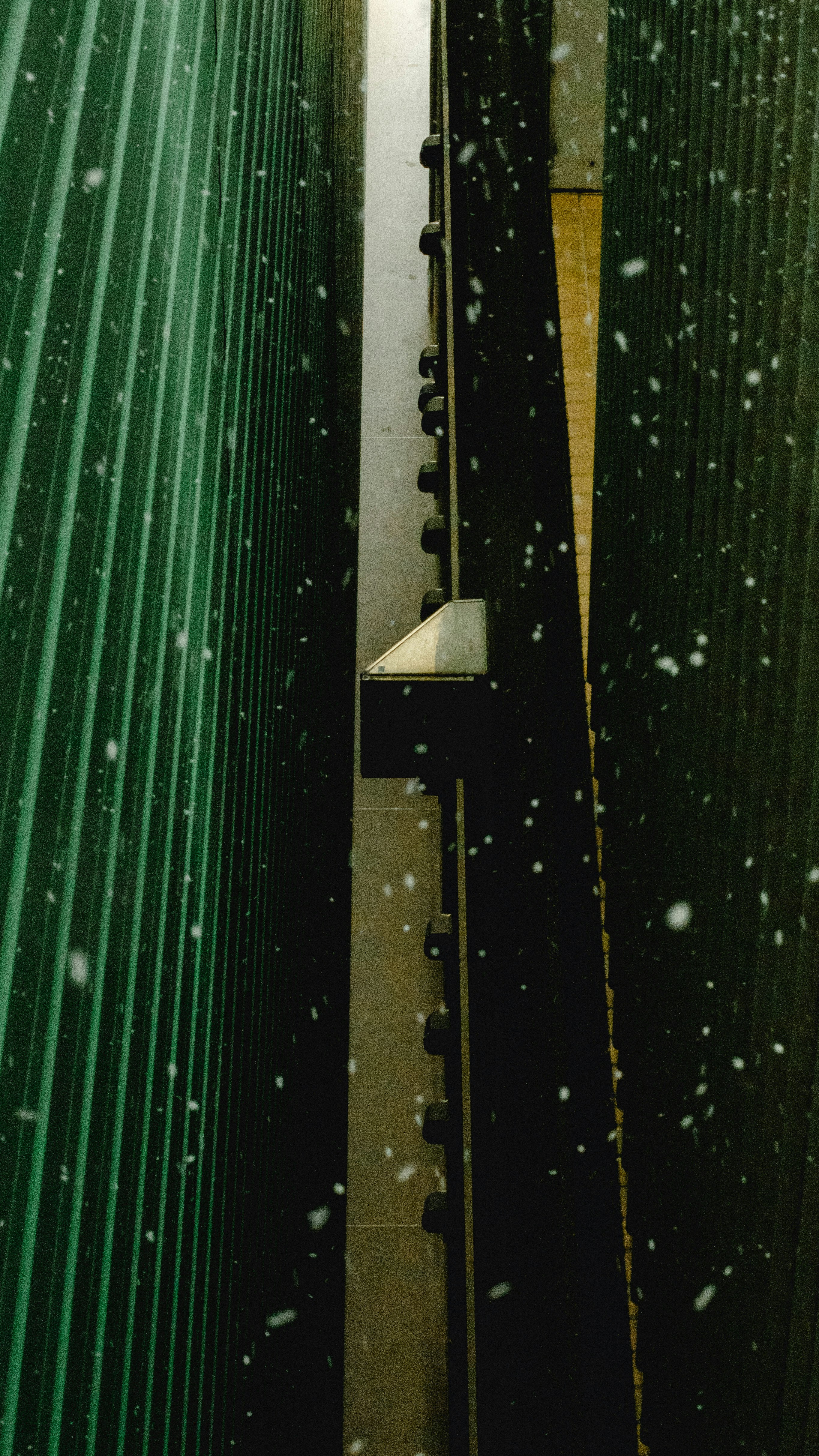 雨滴落在綠色金屬百葉的縫隙間透出的光