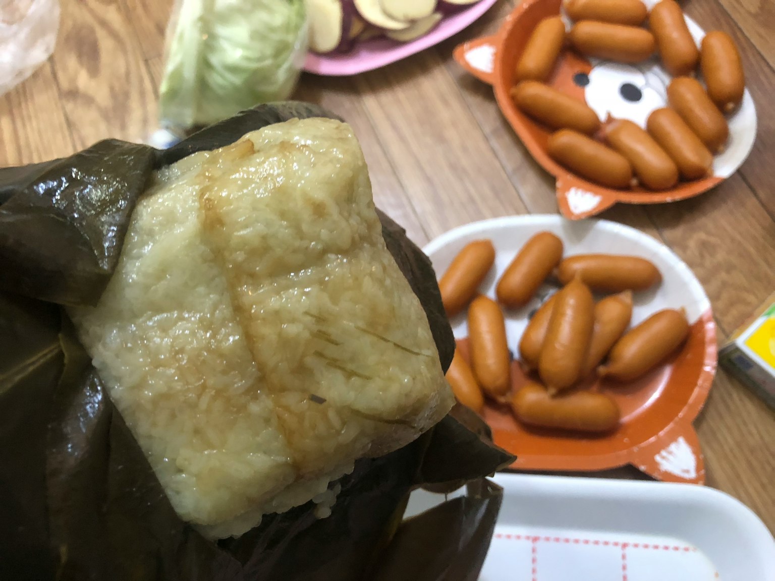 用叶子包裹的米饭团和背景中的各种小吃