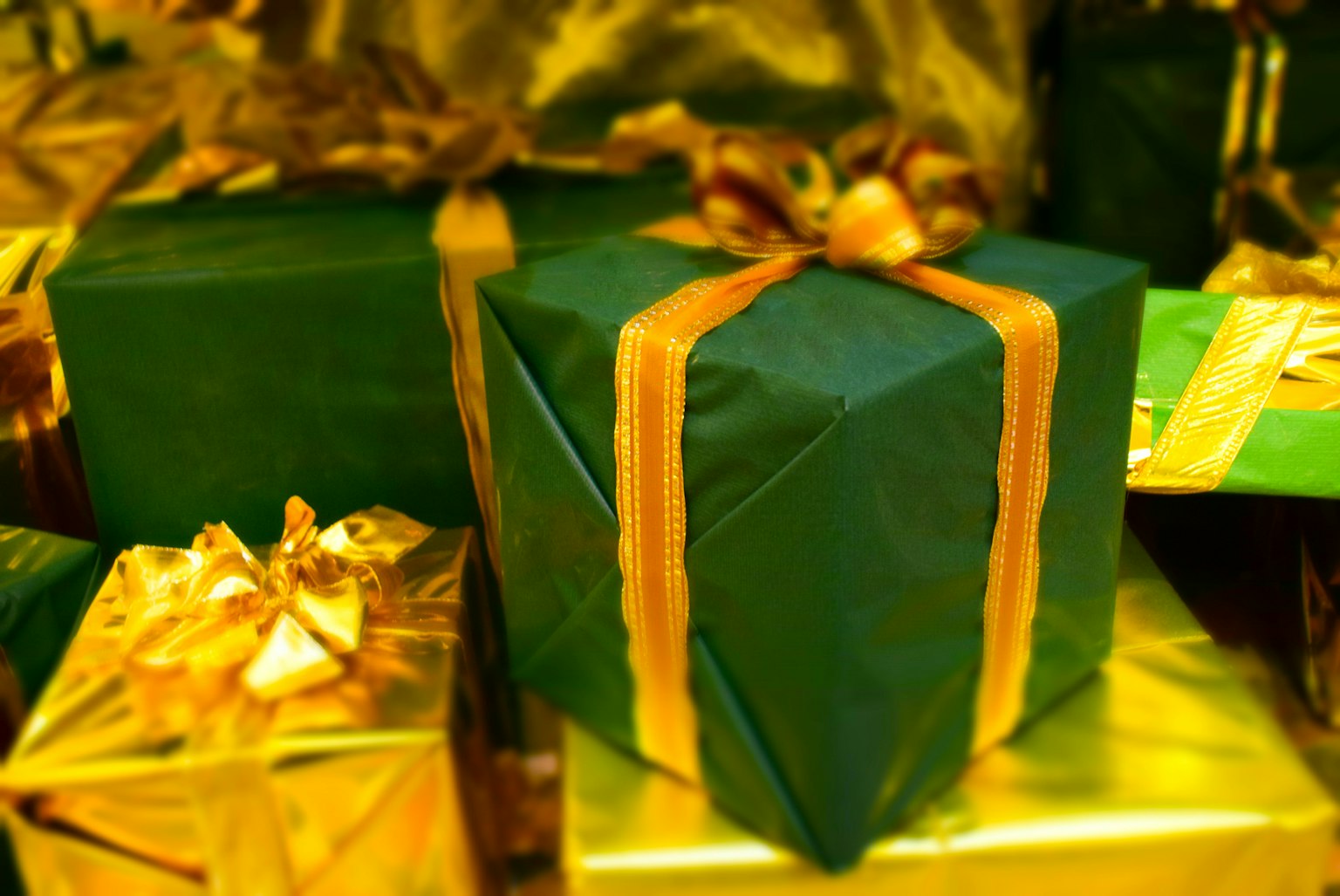 Cadeau emballé en vert avec un ruban doré parmi d'autres cadeaux
