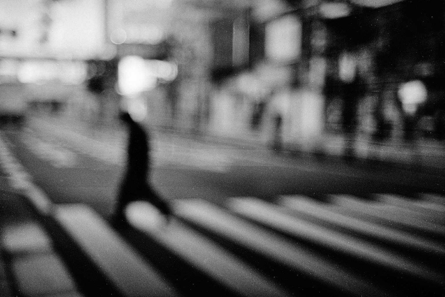 Silhouette sfocata di una persona che attraversa un attraversamento pedonale in bianco e nero
