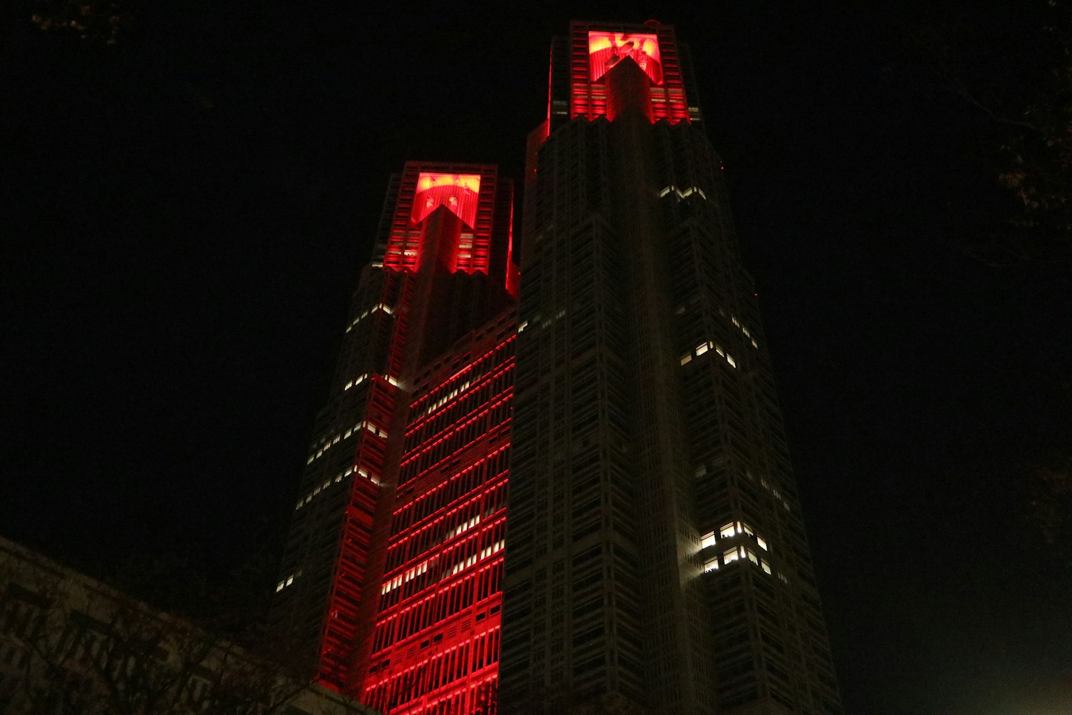 Dua gedung pencakar langit yang diterangi merah di malam hari di Tokyo