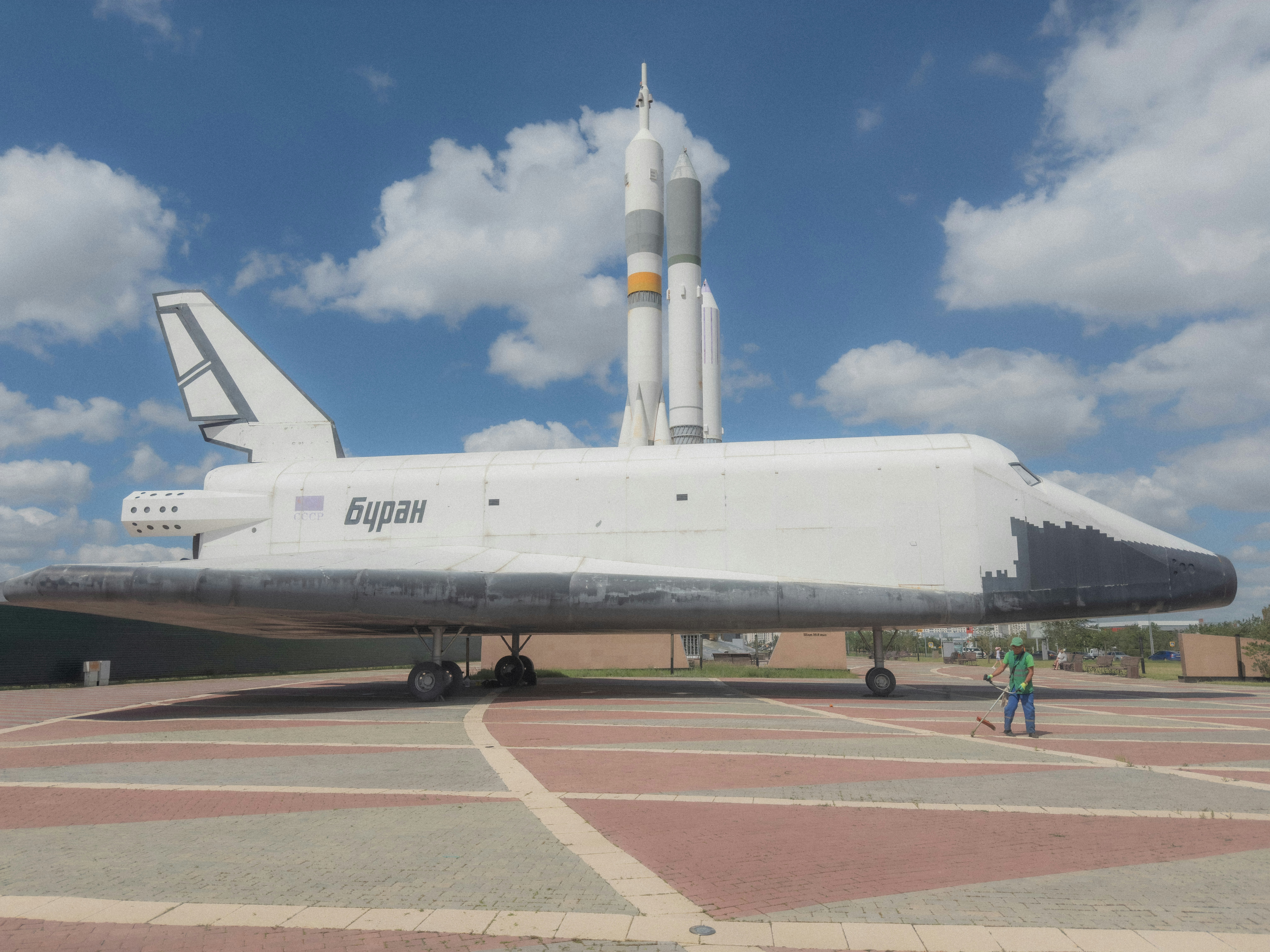 滑走路上の宇宙船のような機体と青空の下の地上風景