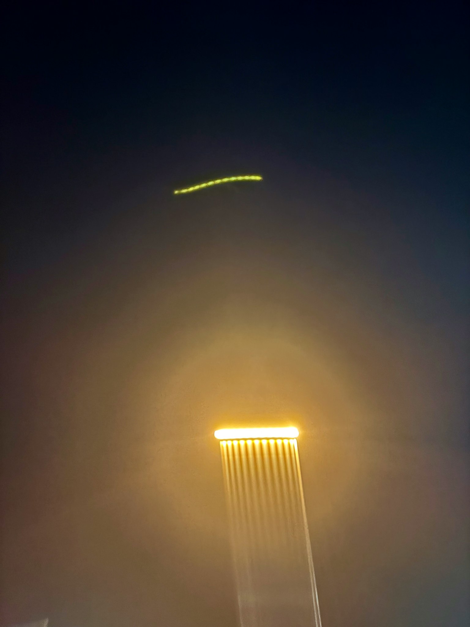 夜空に浮かぶ光の帯と明るい塔の光