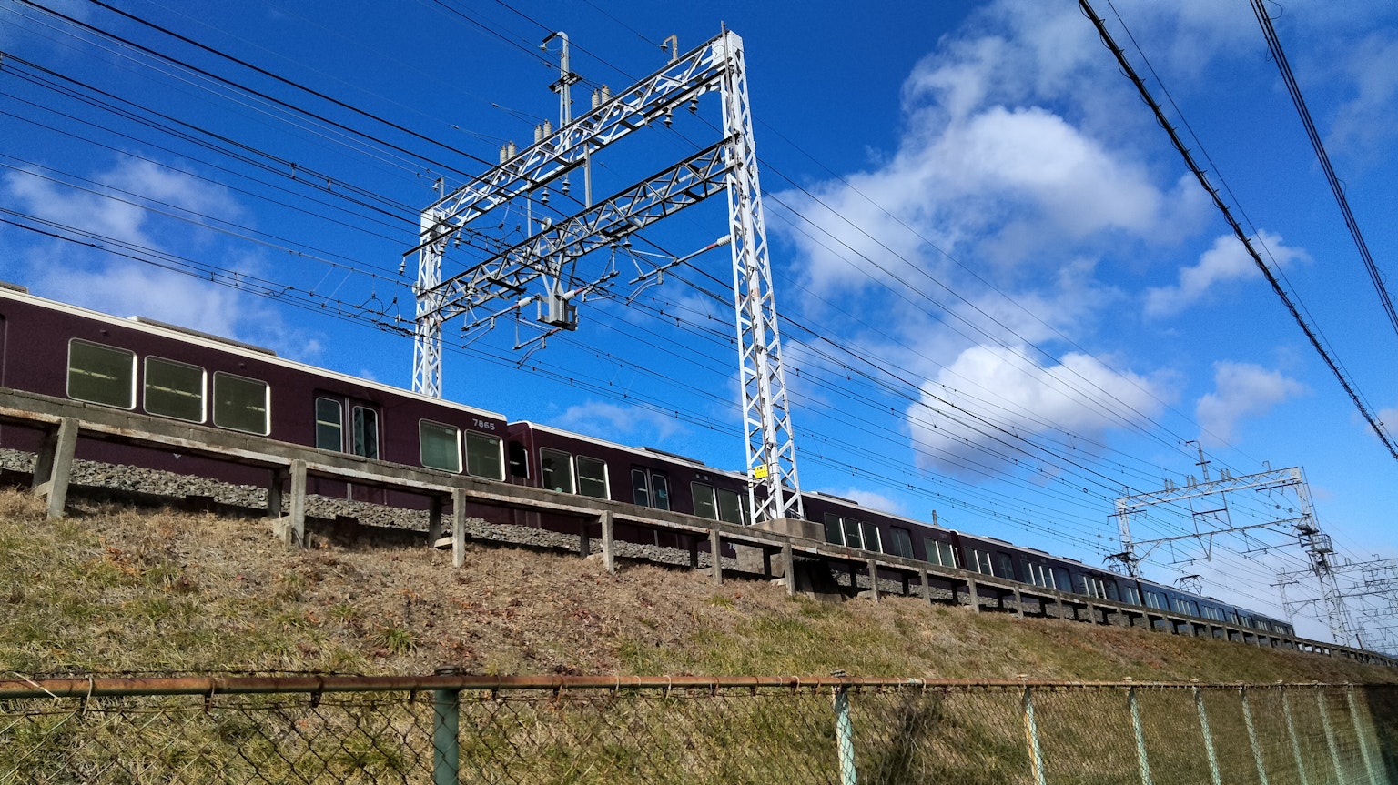 Elevated railway with electric lines under a blue sky
