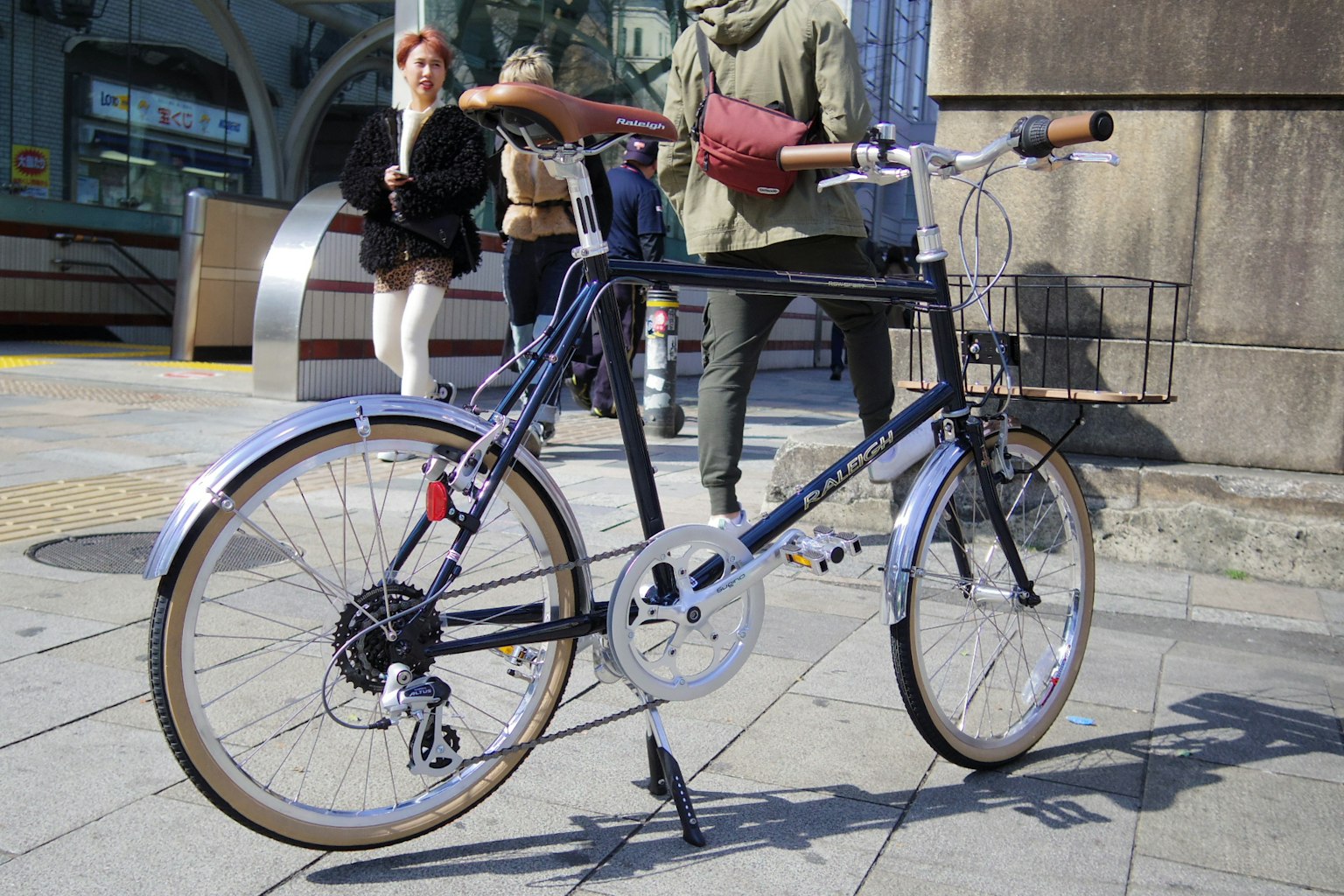 Una bicicletta blu parcheggiata per strada con persone sullo sfondo
