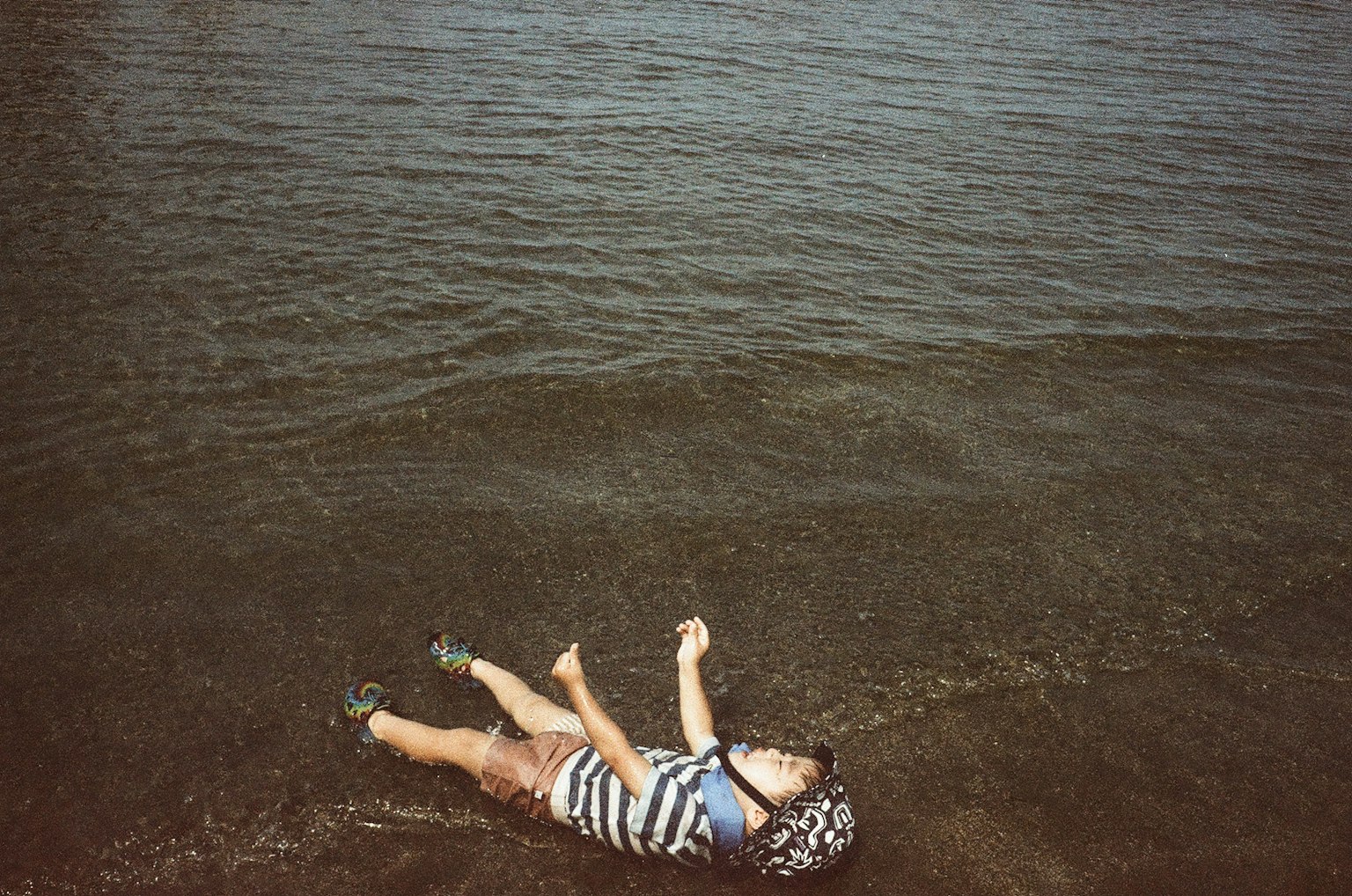 水辺で寝転ぶ子供の姿