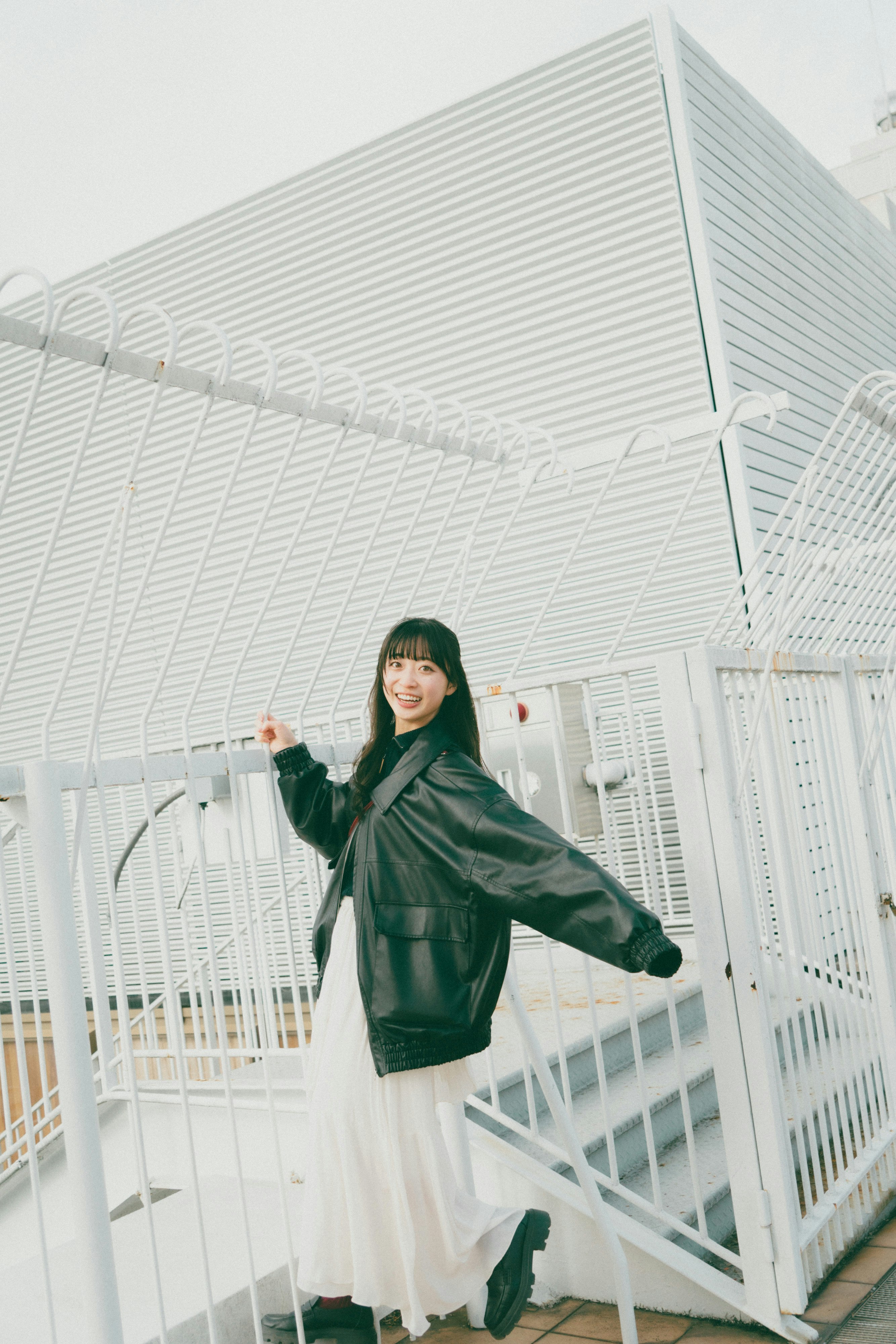 白い近未来的な建物の外階段でポーズをとる女性
