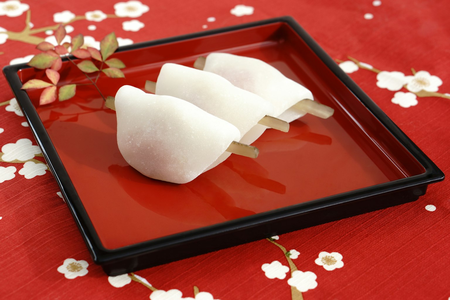 Piring cantik dengan wagashi putih di latar belakang merah