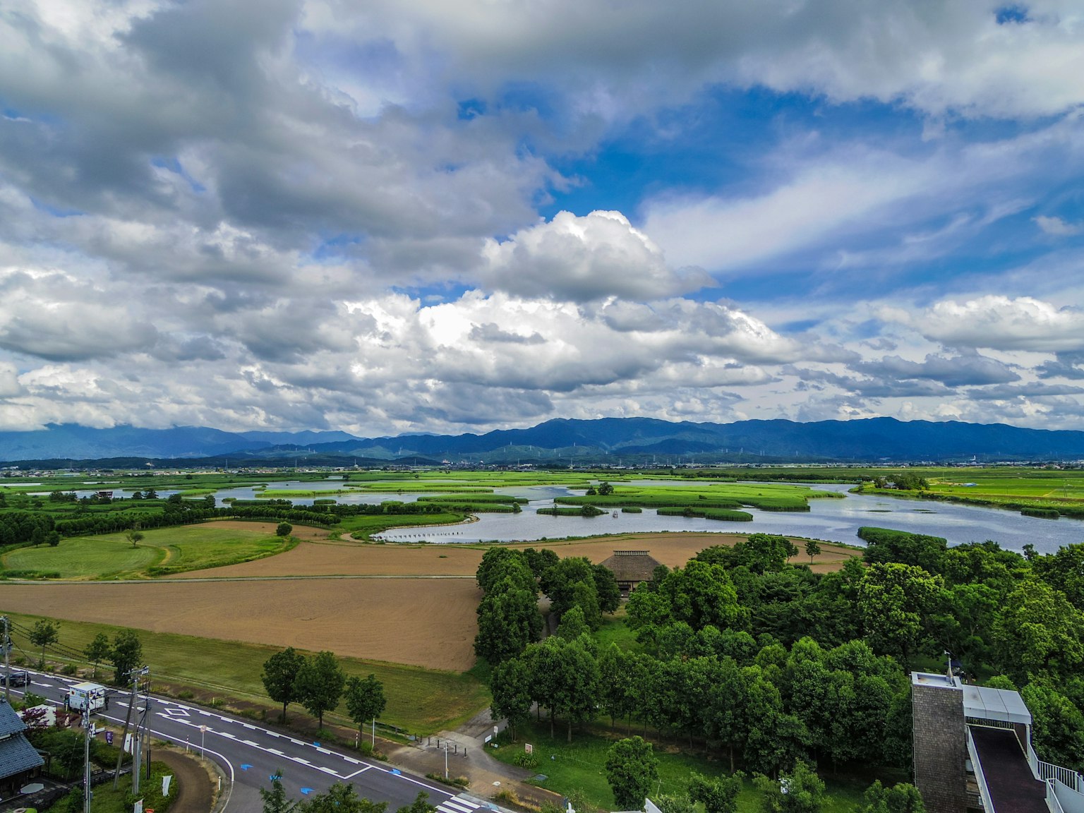 Scenic view featuring blue sky with clouds green fields and a river