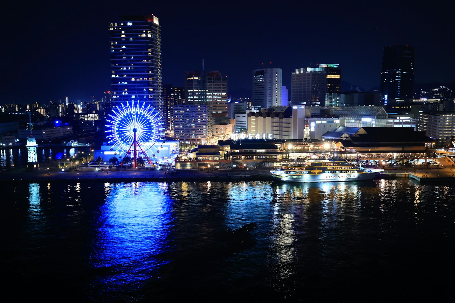 Paysage urbain nocturne avec une grande roue bleue et des bâtiments lumineux