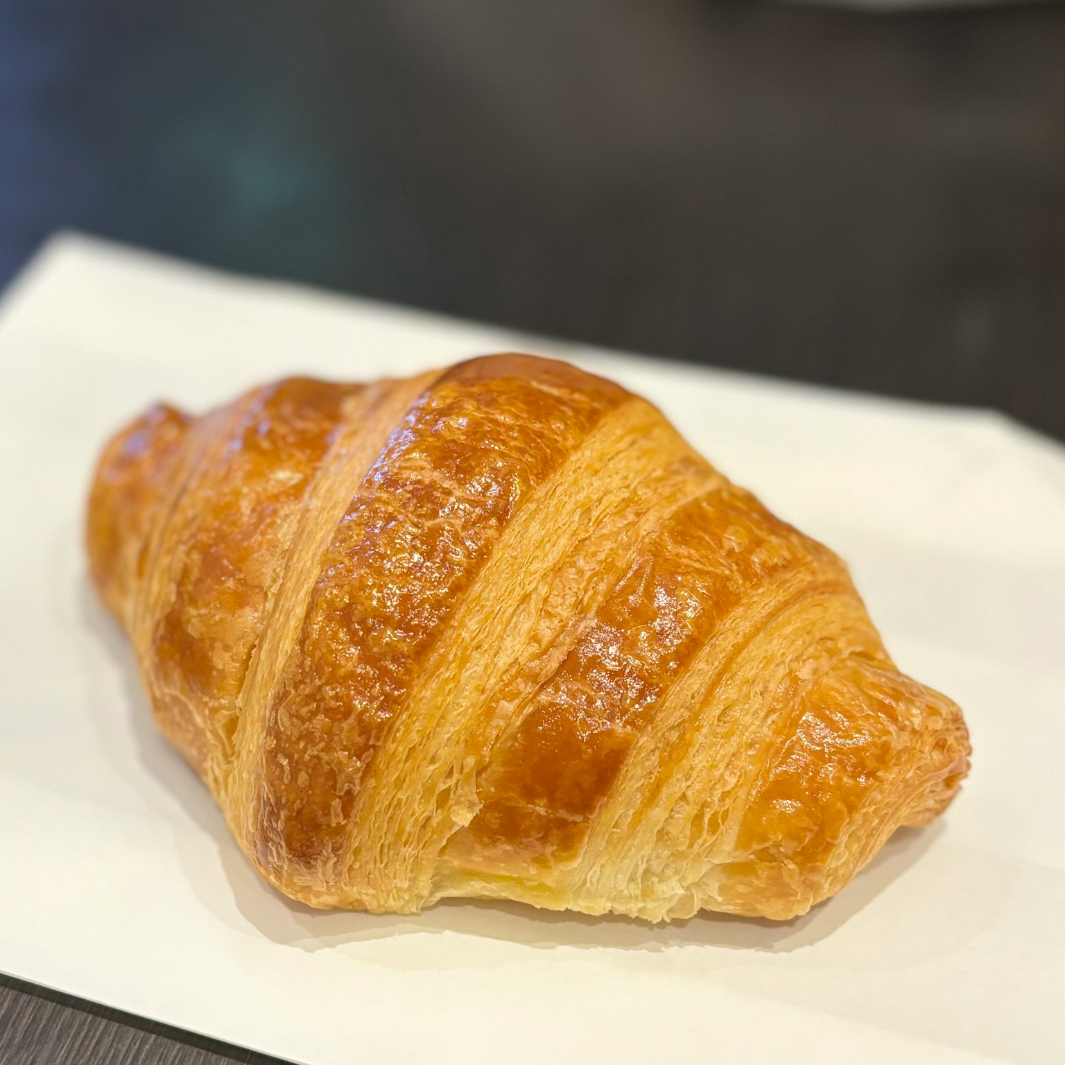 Ein goldbrauner Croissant auf einem weißen Papier