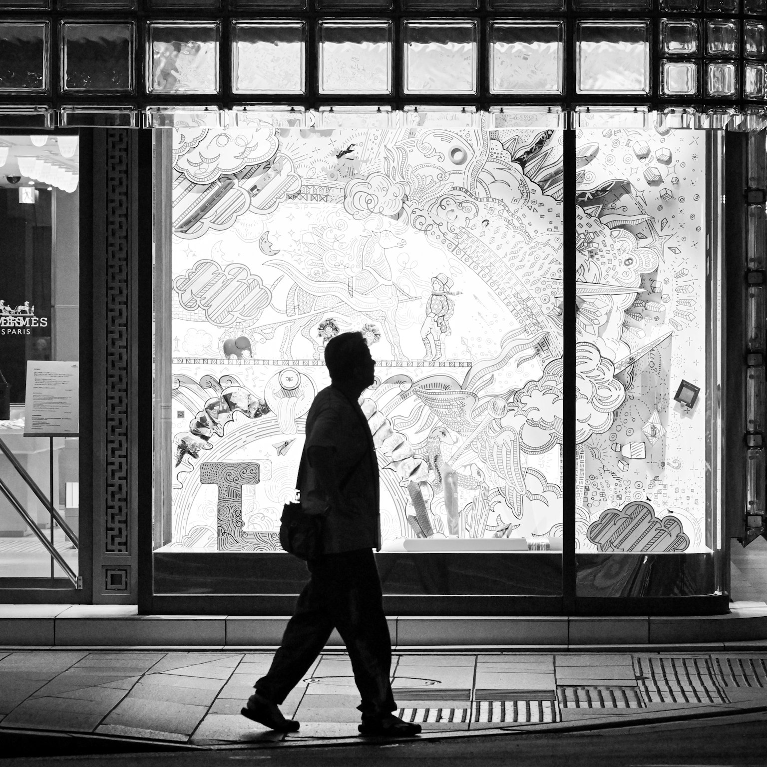 Silhouette di una persona che cammina davanti a una vetrina in bianco e nero