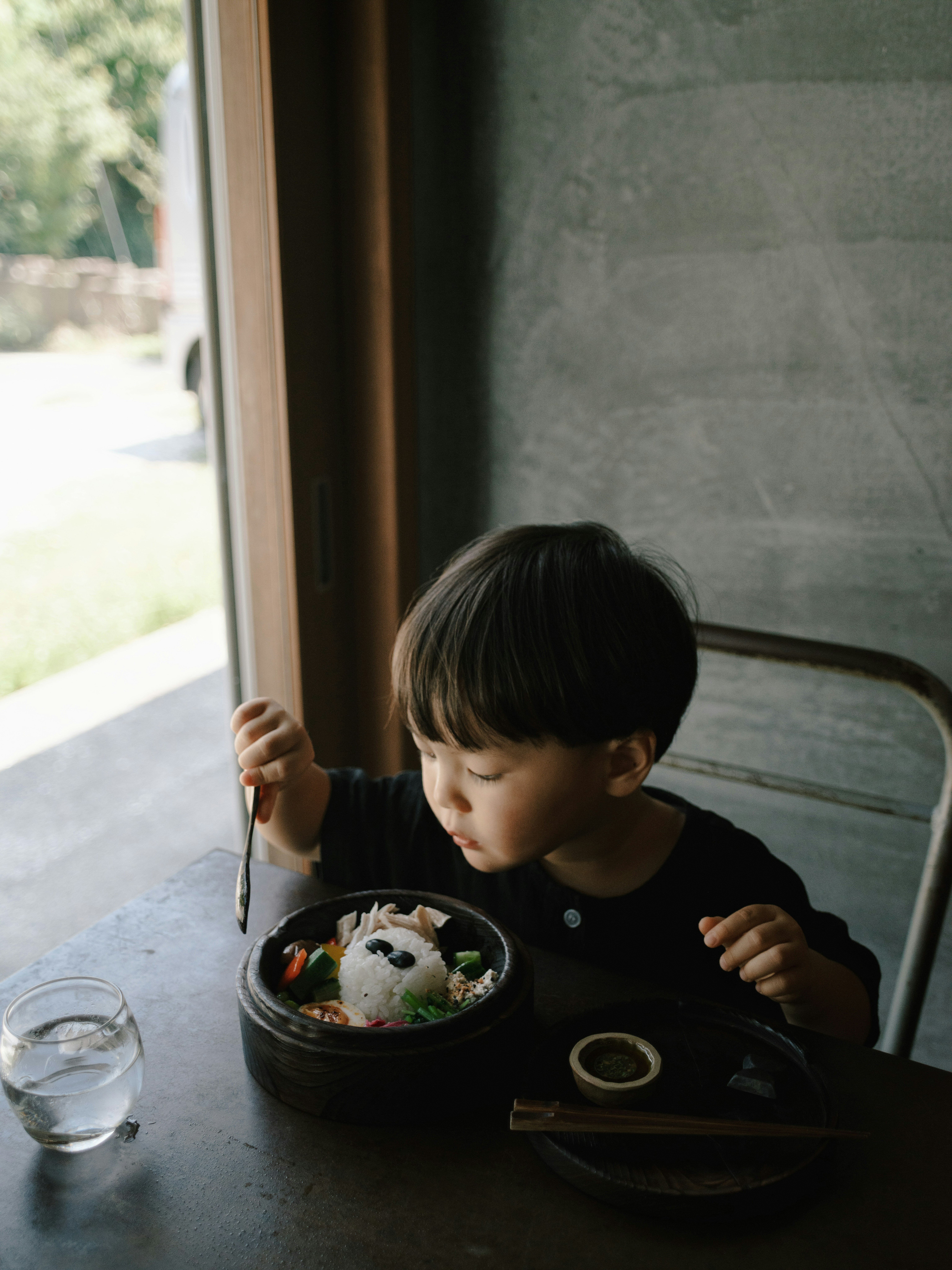 窓辺でお弁当を食べる子どもの食卓