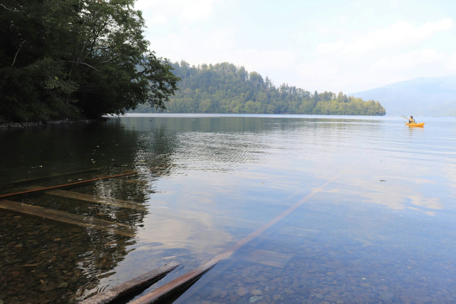 Serene lake landscape with distant mountains and a small boat