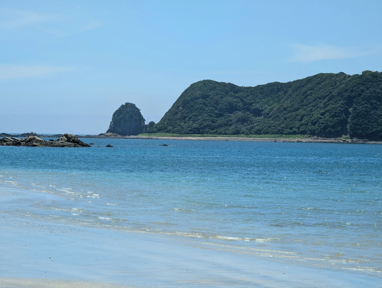 Pemandangan pantai yang indah dengan laut biru dan gunung hijau