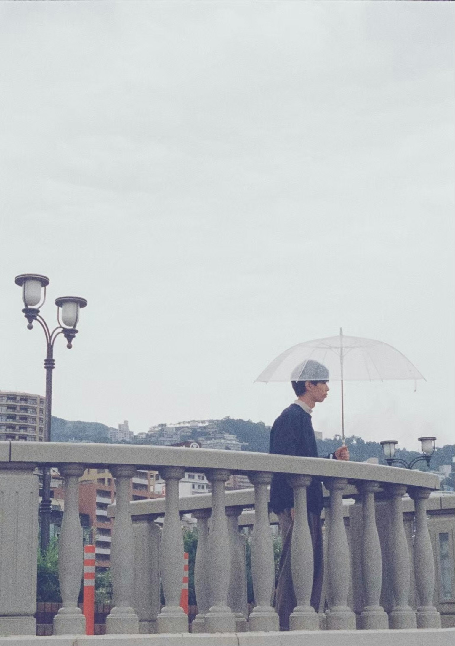 一个站在桥上拿着伞的男人