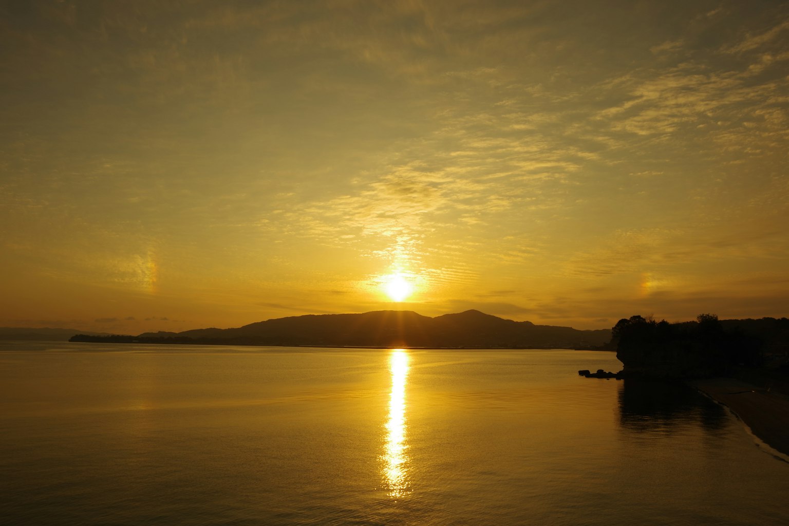 Beautiful landscape of sunset over mountains with warm orange reflection on calm water
