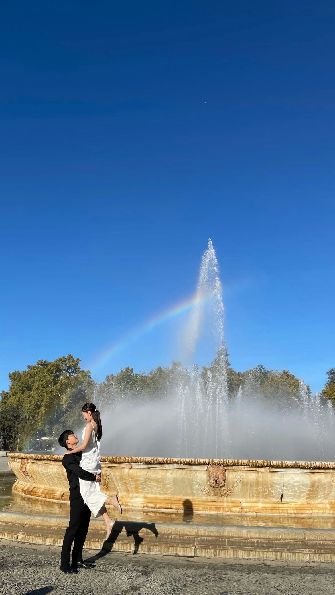 スペイン・セビリアの広場で噴水の前に立つ前撮りカップル