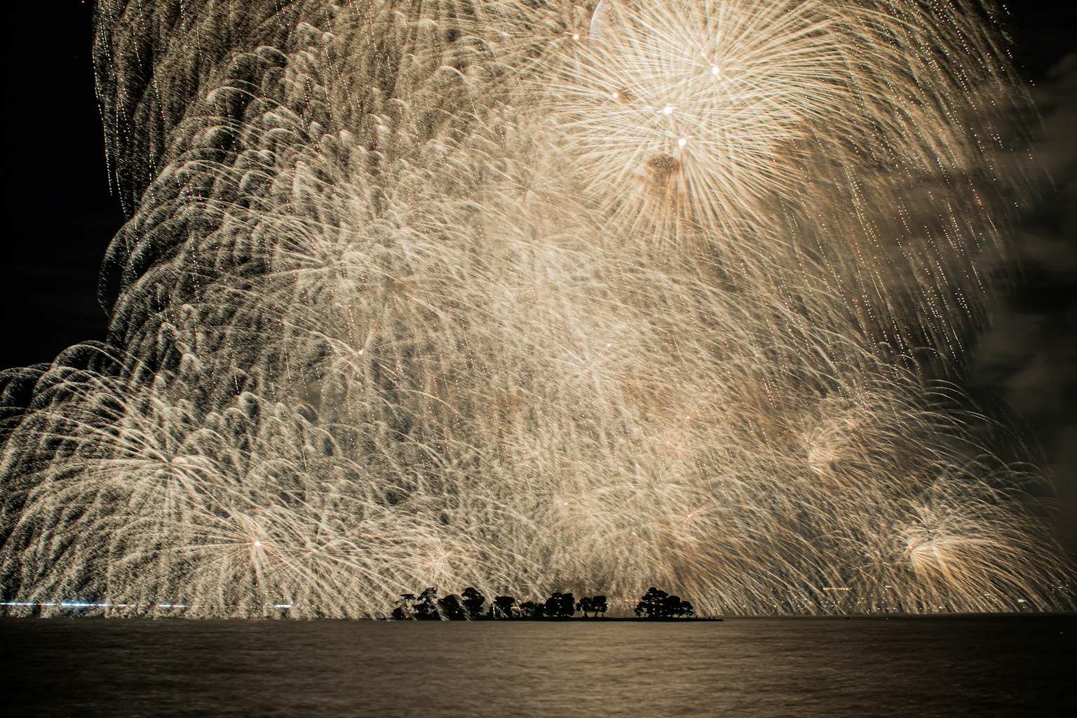 Bellissimi fuochi d'artificio che illuminano il cielo notturno riflessi sulla superficie dell'acqua