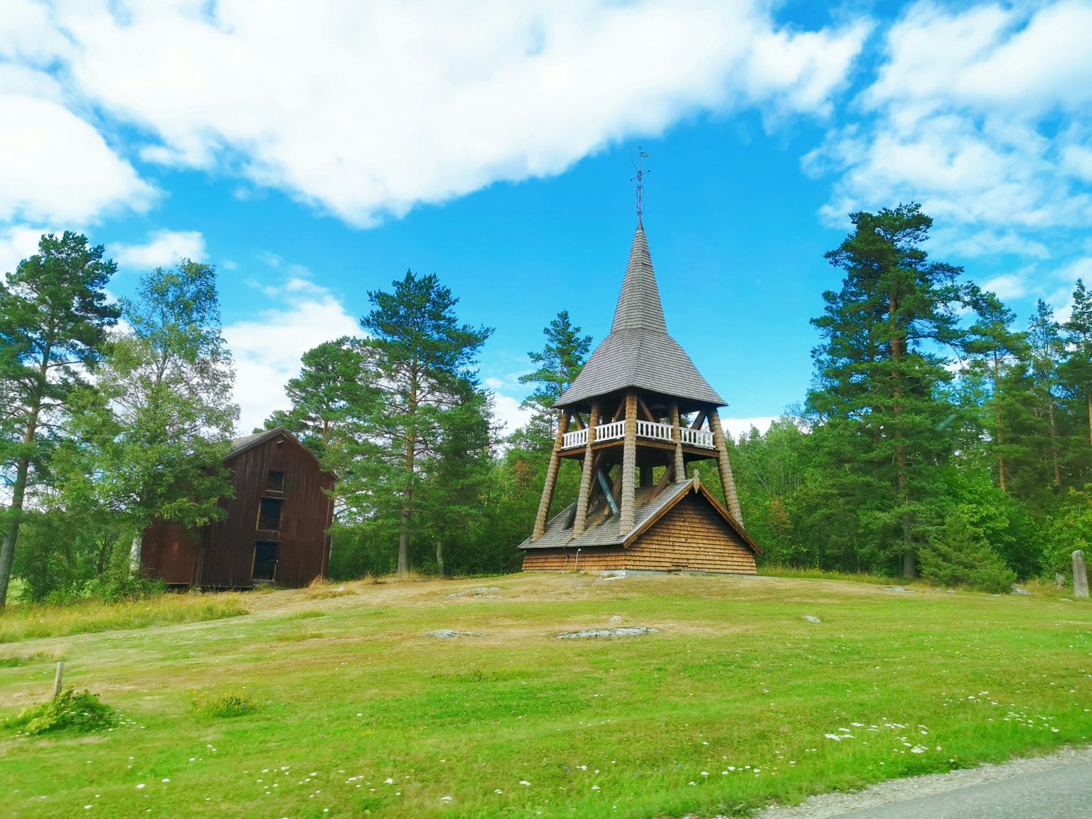 Scenic view featuring a wooden bell tower with a pointed roof and an old building