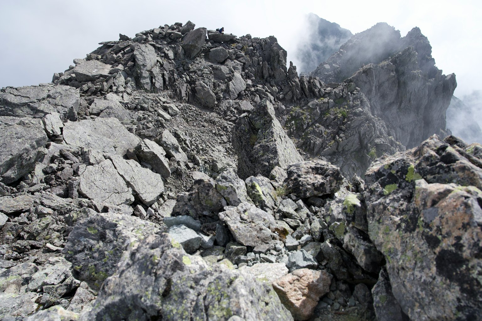 Pemandangan berbatu yang terjal dengan puncak gunung yang mendung