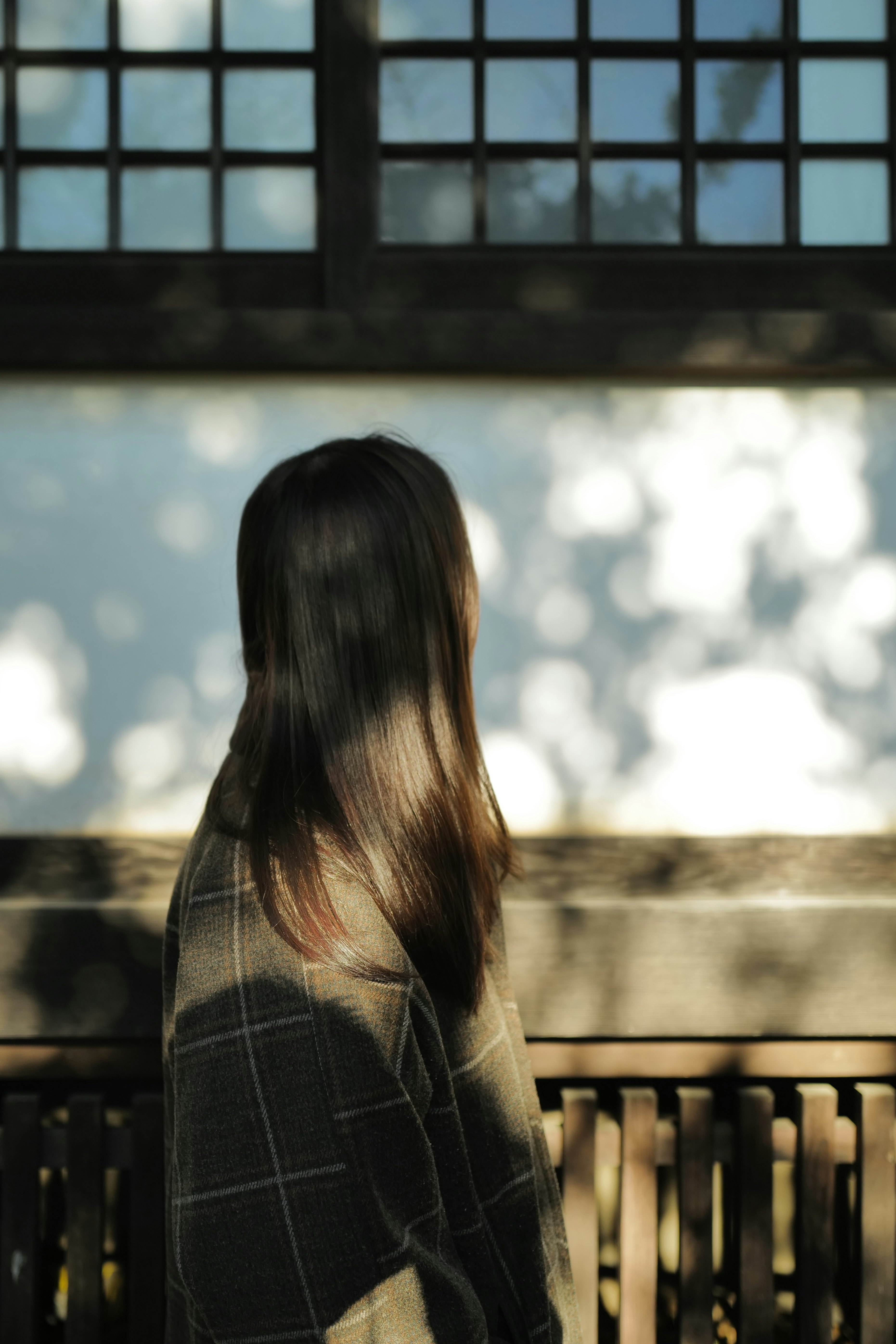 窓辺のベンチに座る長い髪の人物