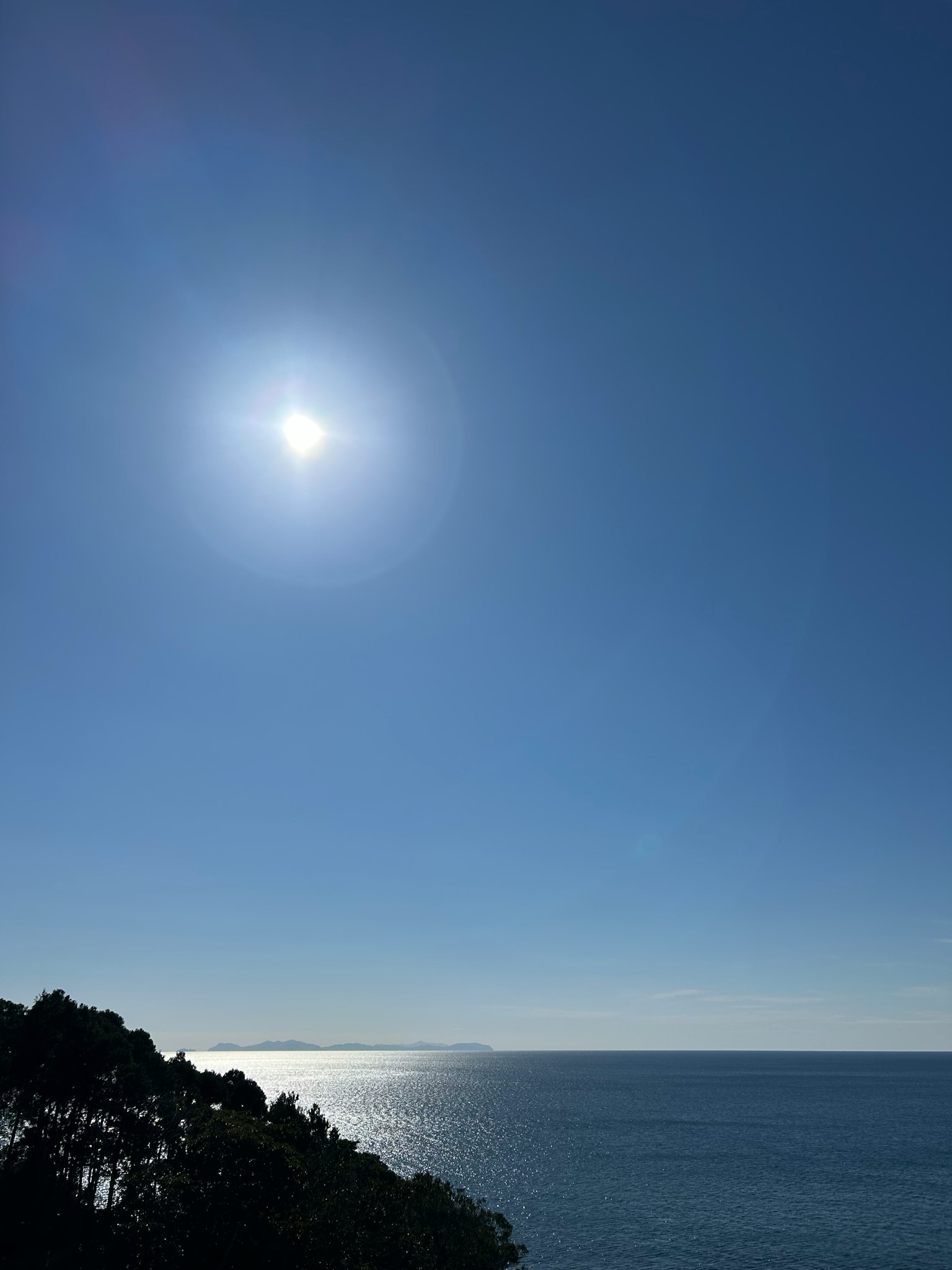 Sole luminoso sopra un oceano blu calmo e cielo sereno