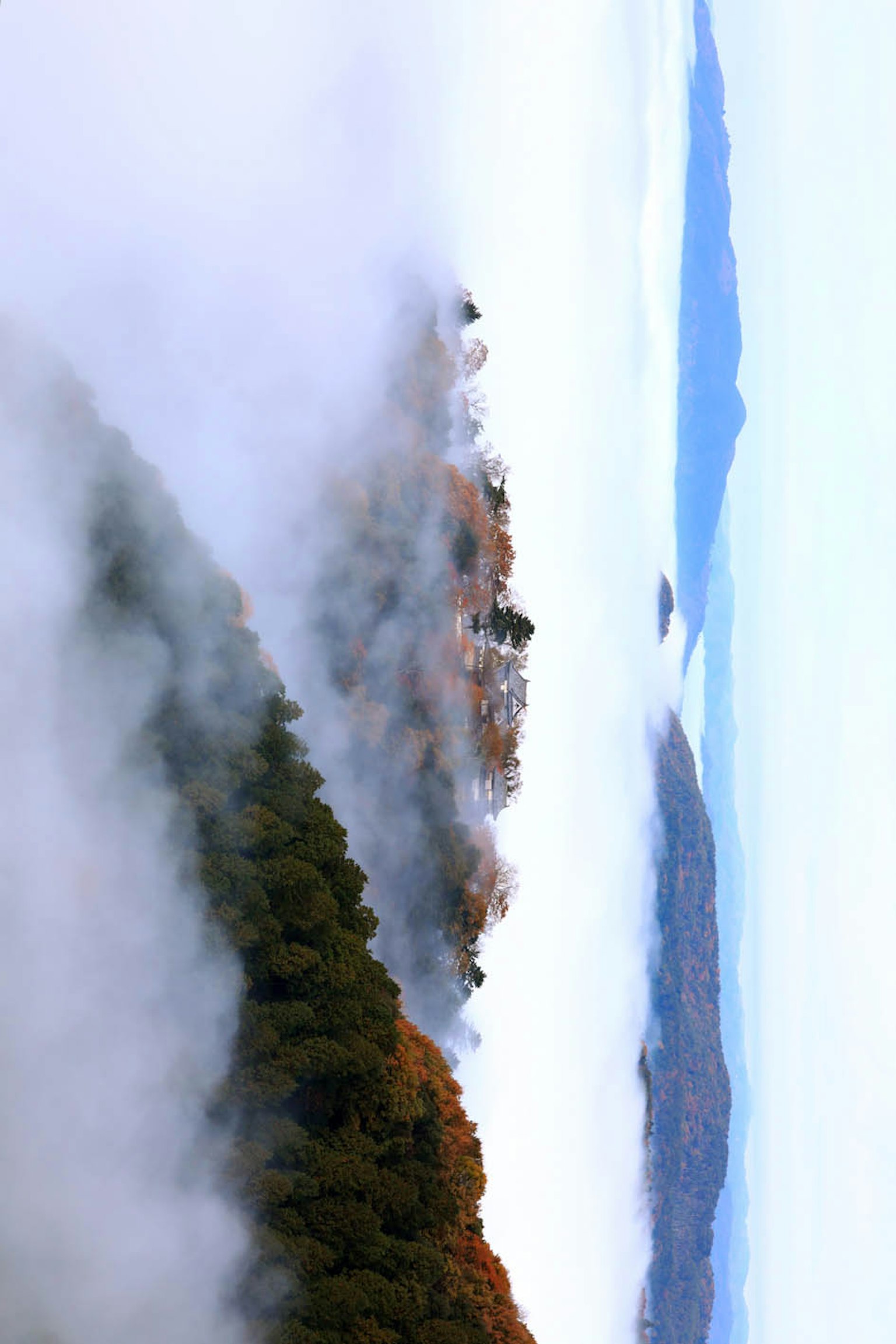 Mountain landscape shrouded in fog with a serene lake