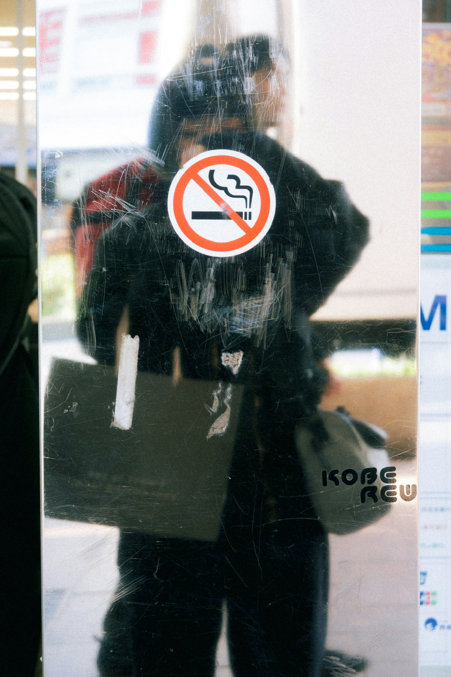 鏡に映る人物と禁煙マークのサインがある風景