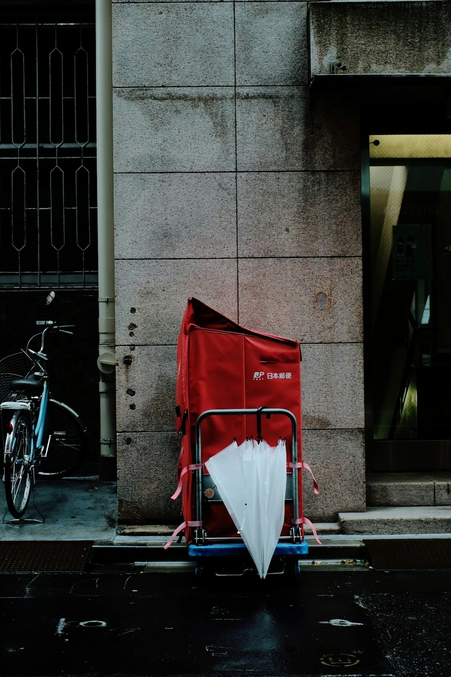 Carrello rosso appoggiato a un muro con un ombrello bianco in un contesto cittadino