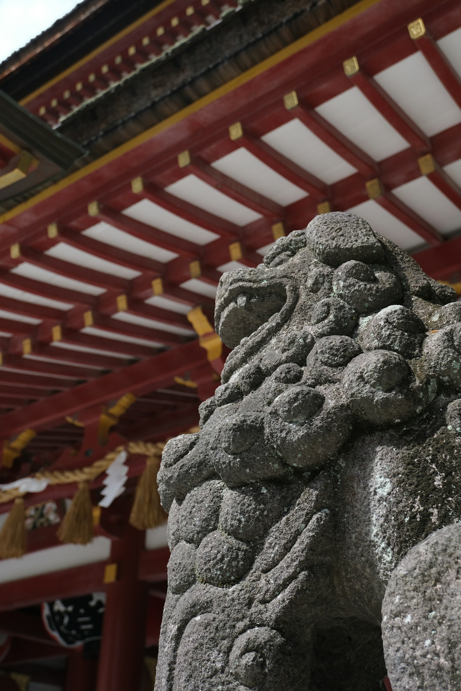 Escultura de león guardián de piedra en un templo de techo rojo