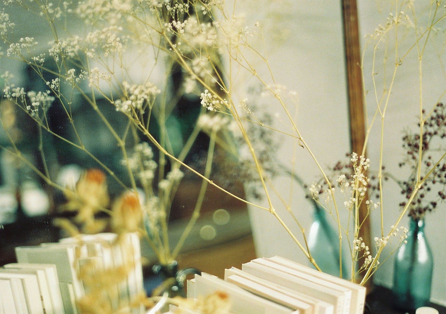 Un tavolo con libri bianchi e composizioni di fiori secchi