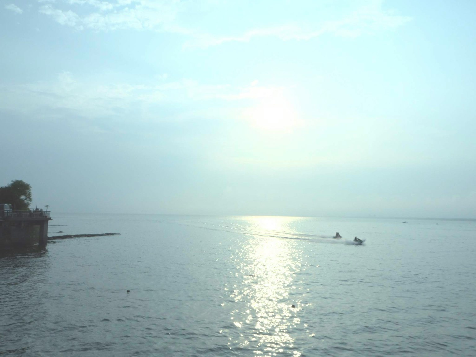 Calm water reflecting the sunrise with silhouettes of fishing boats