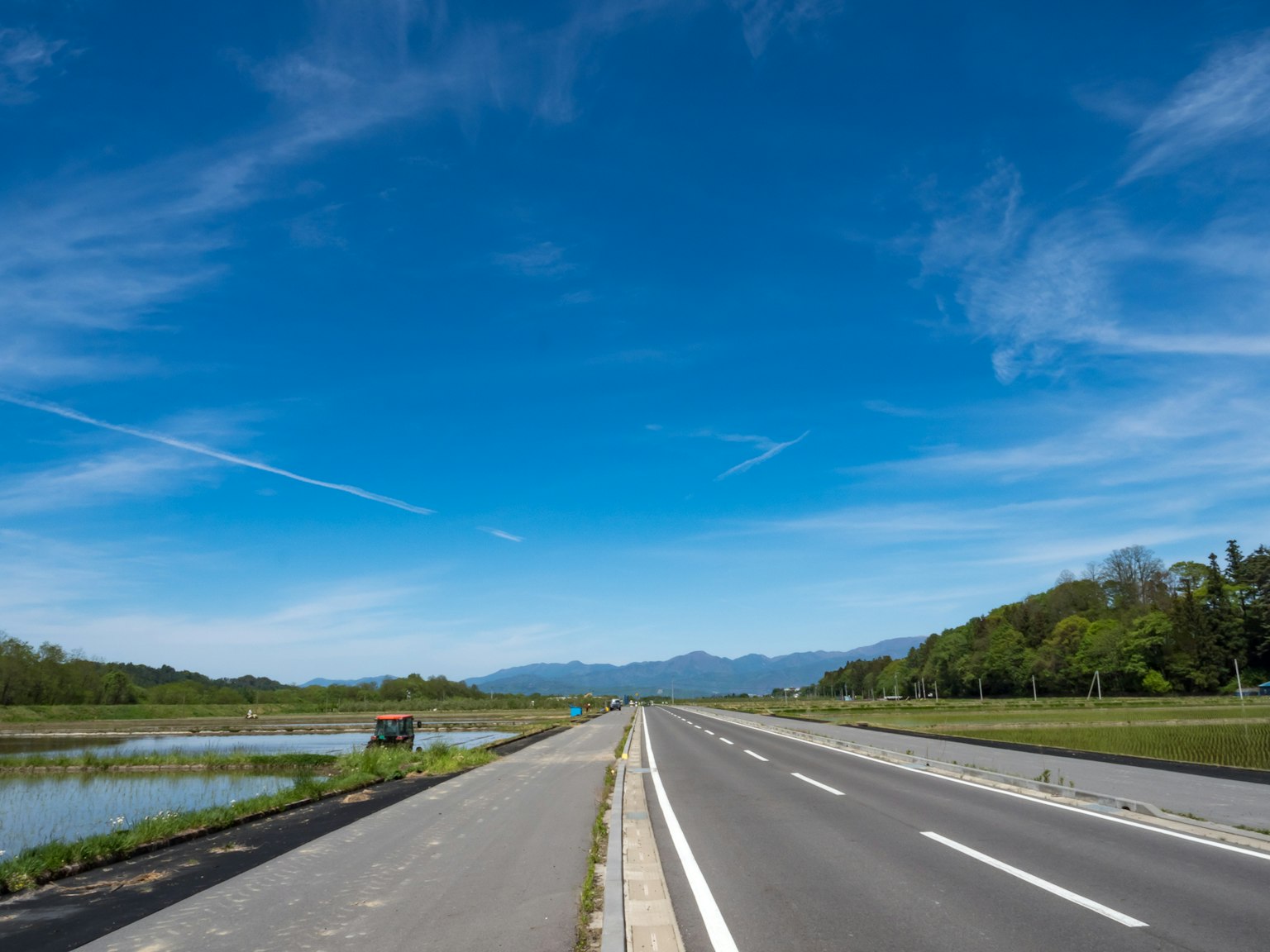 Breite Straße unter einem blauen Himmel mit üppigem Grün