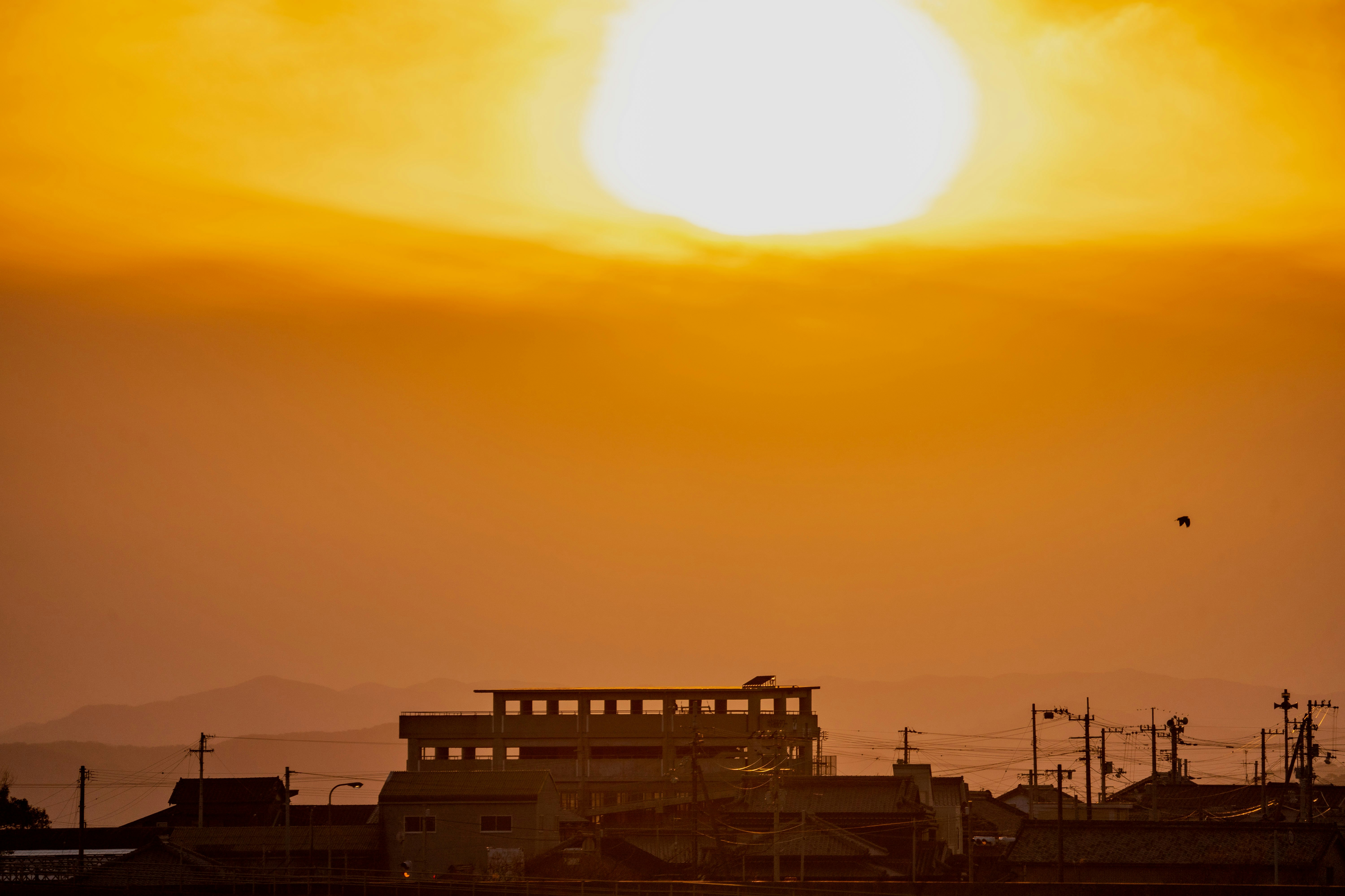 Industriegebäude und Stromleitungen in einer von Sonnenuntergang beleuchteten Stadtansicht