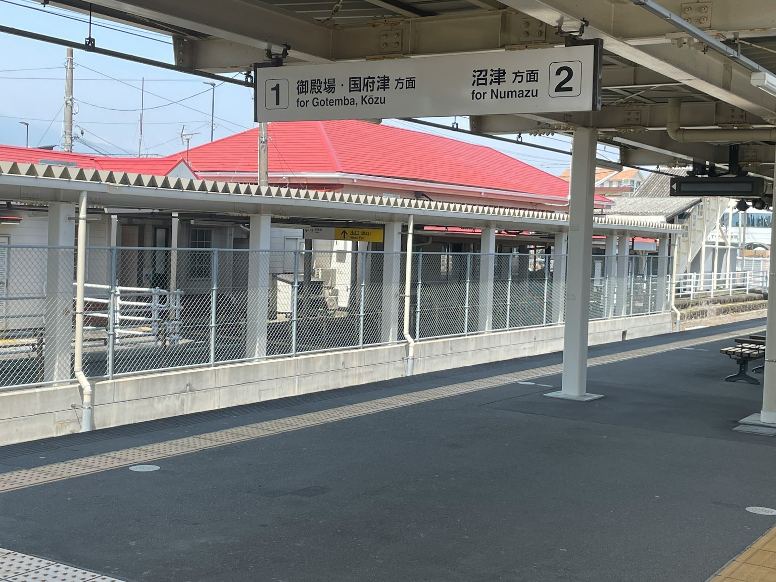 มุมมองของชานชาลาสถานีรถไฟพร้อมป้ายและอาคารหลังคาสีแดง