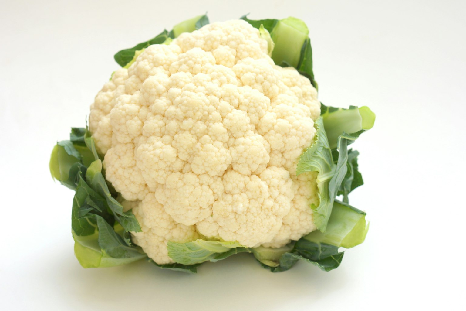 Frischer Blumenkohlkopf auf grünen Blättern