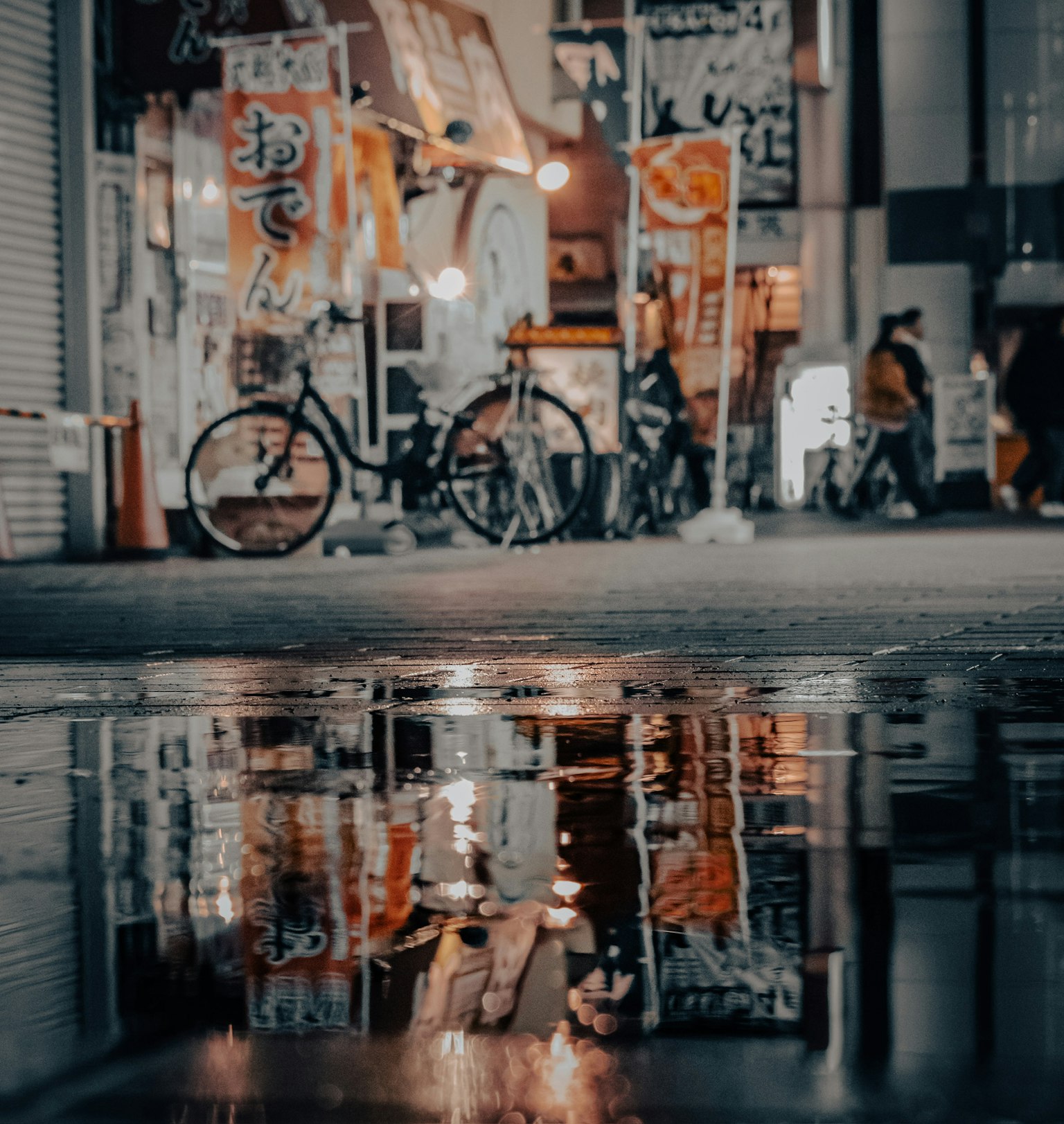 湿润路面上反射的自行车和街头小贩的灯光