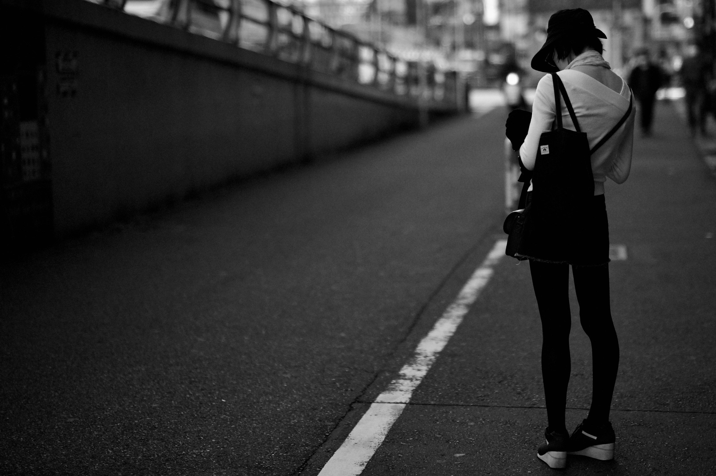モノクロの路地を歩く人の後ろ姿