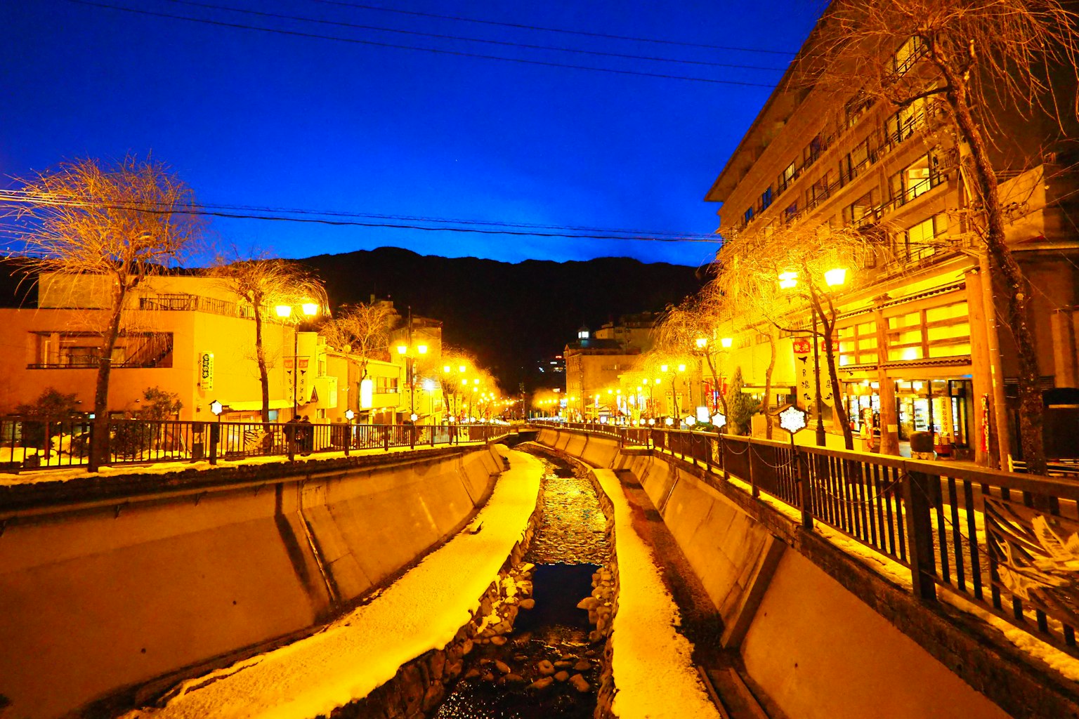 Scène nocturne d'une ville thermale avec des lampadaires lumineux et un ciel bleu