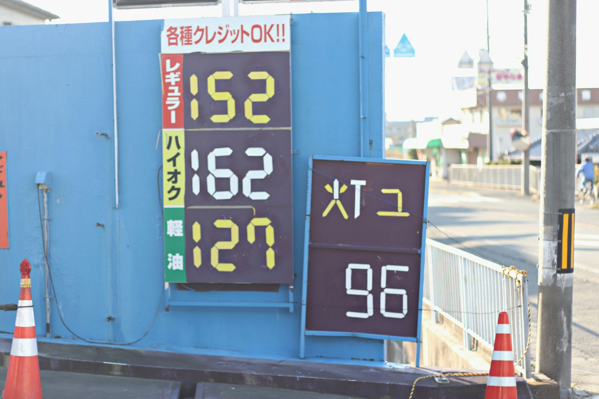 blue electronic price boards with numbers and a roadside scene