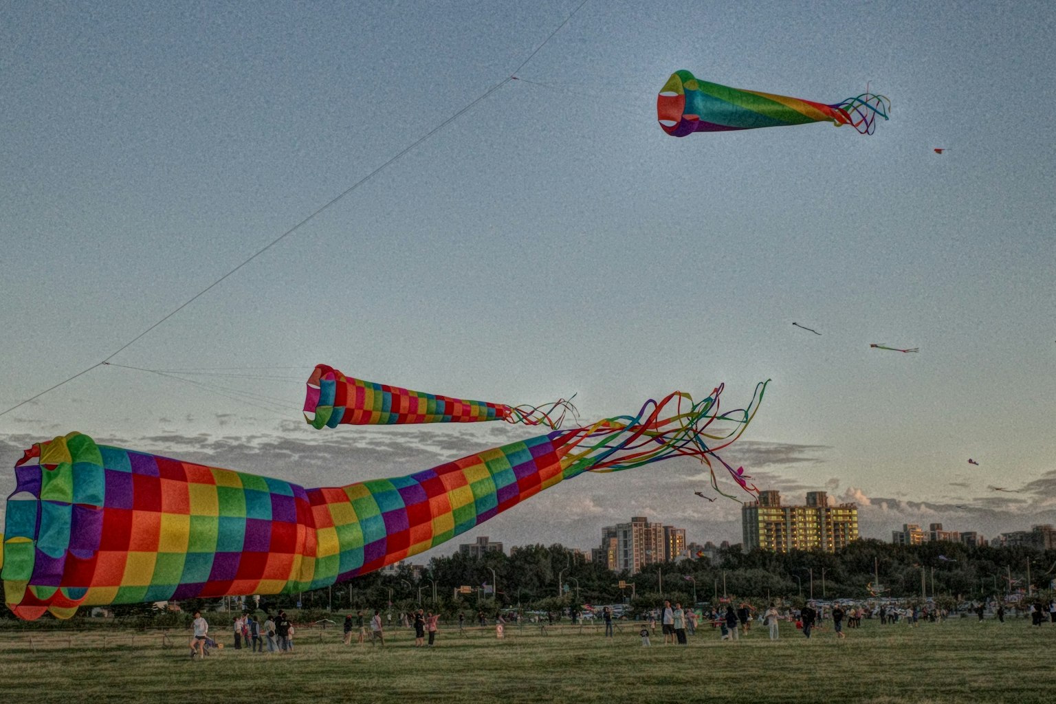 カラフルな凧が空に舞い上がる風景　青空と夕焼けの背景　公園での凧揚げイベント