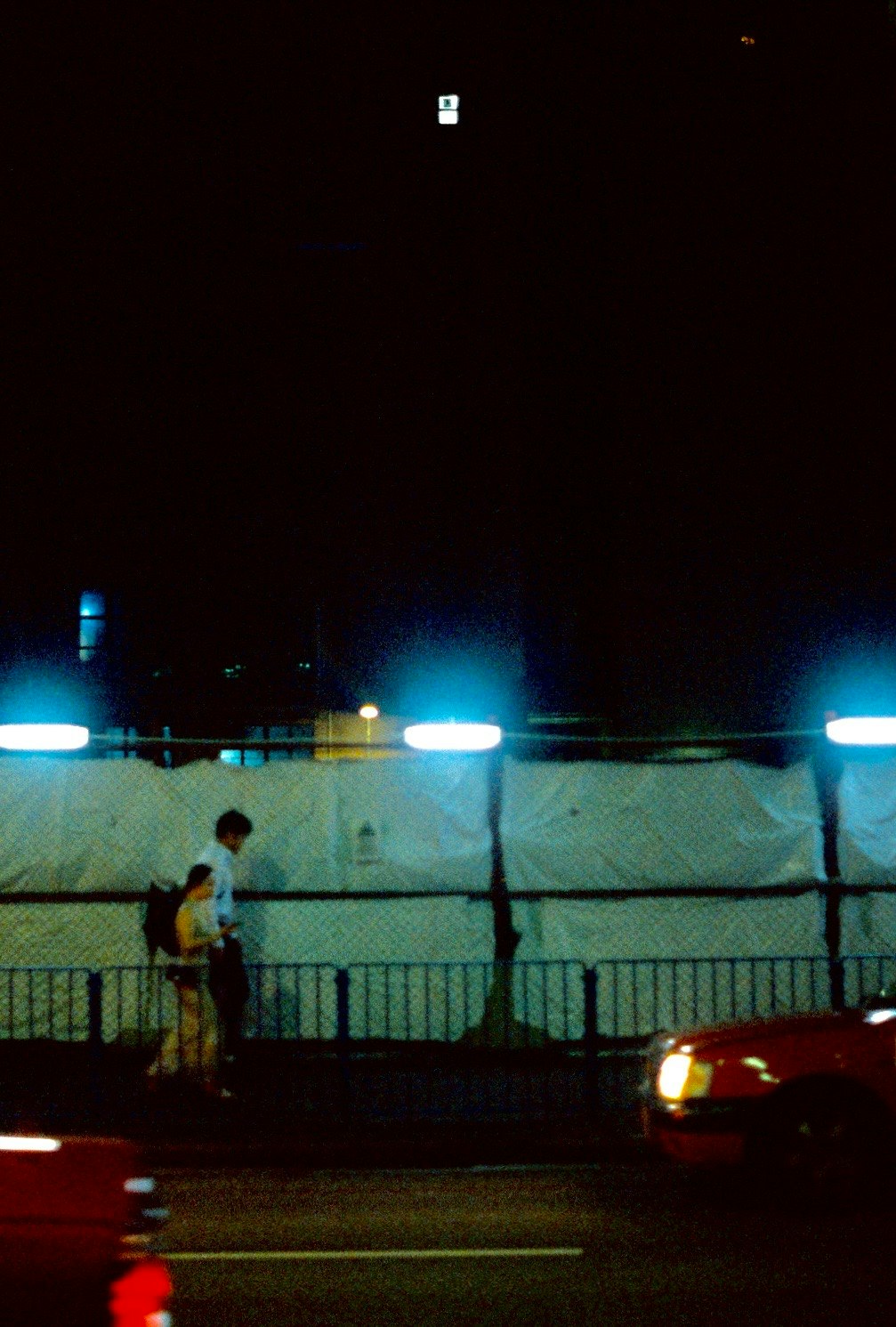 夜の港でフェンス越しに見える海沿いの街灯と車