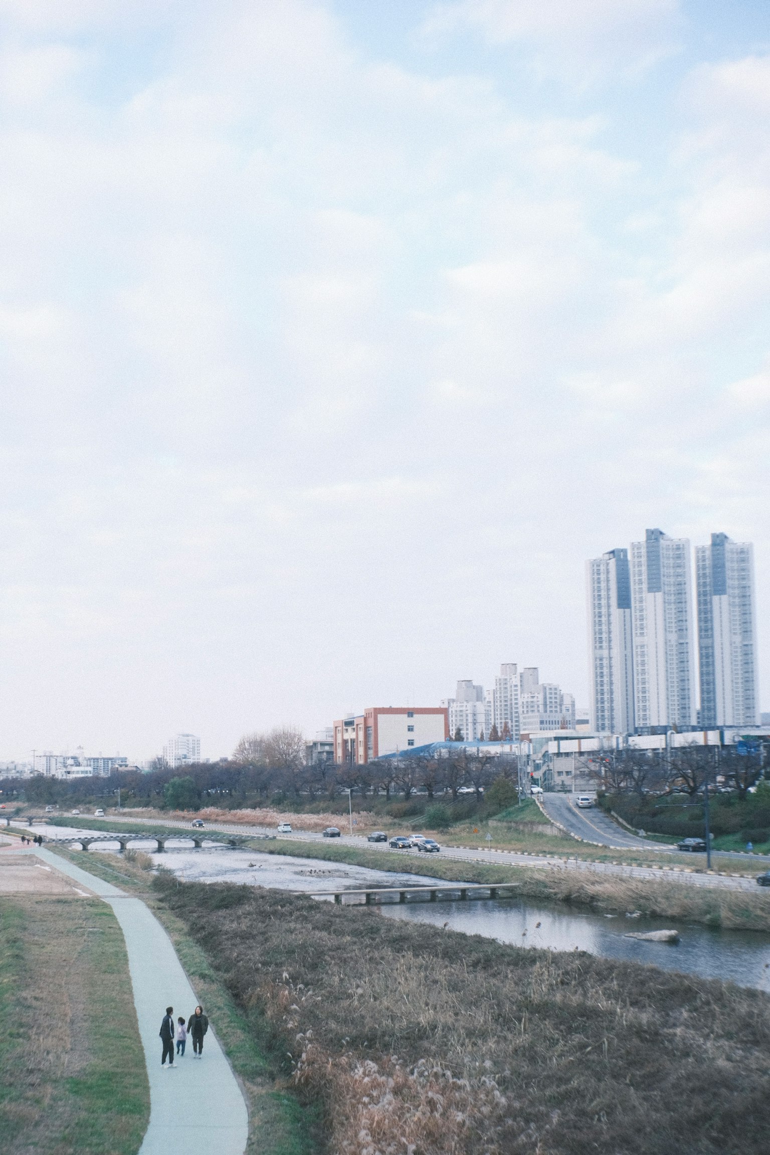 沿河步道行走的人与背景中的摩天大楼