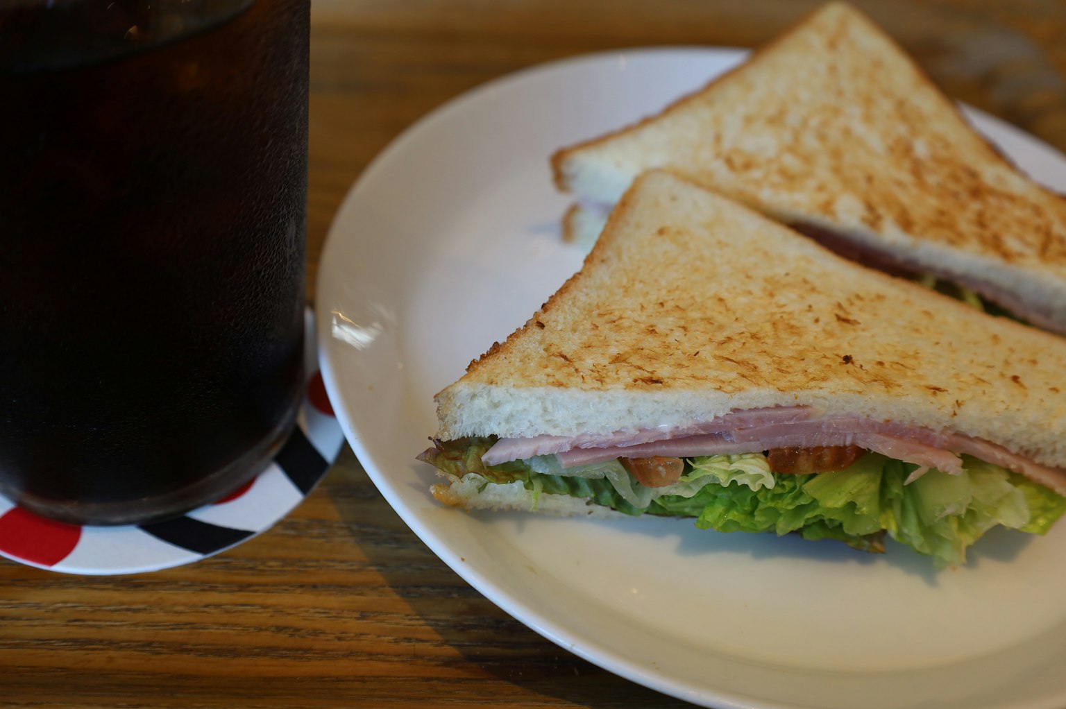 Sándwich tostado con lechuga y jamón junto a té helado