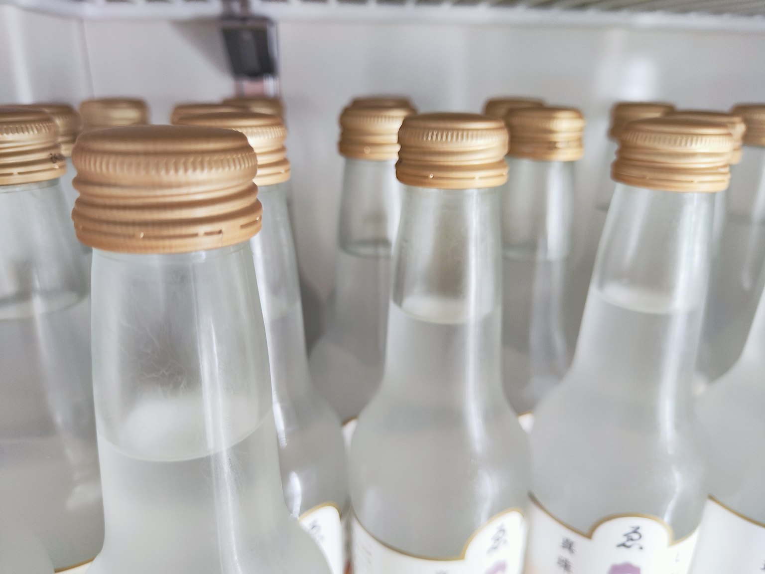 Sắp xếp các chai trong suốt với nắp vàng trong tủ lạnh