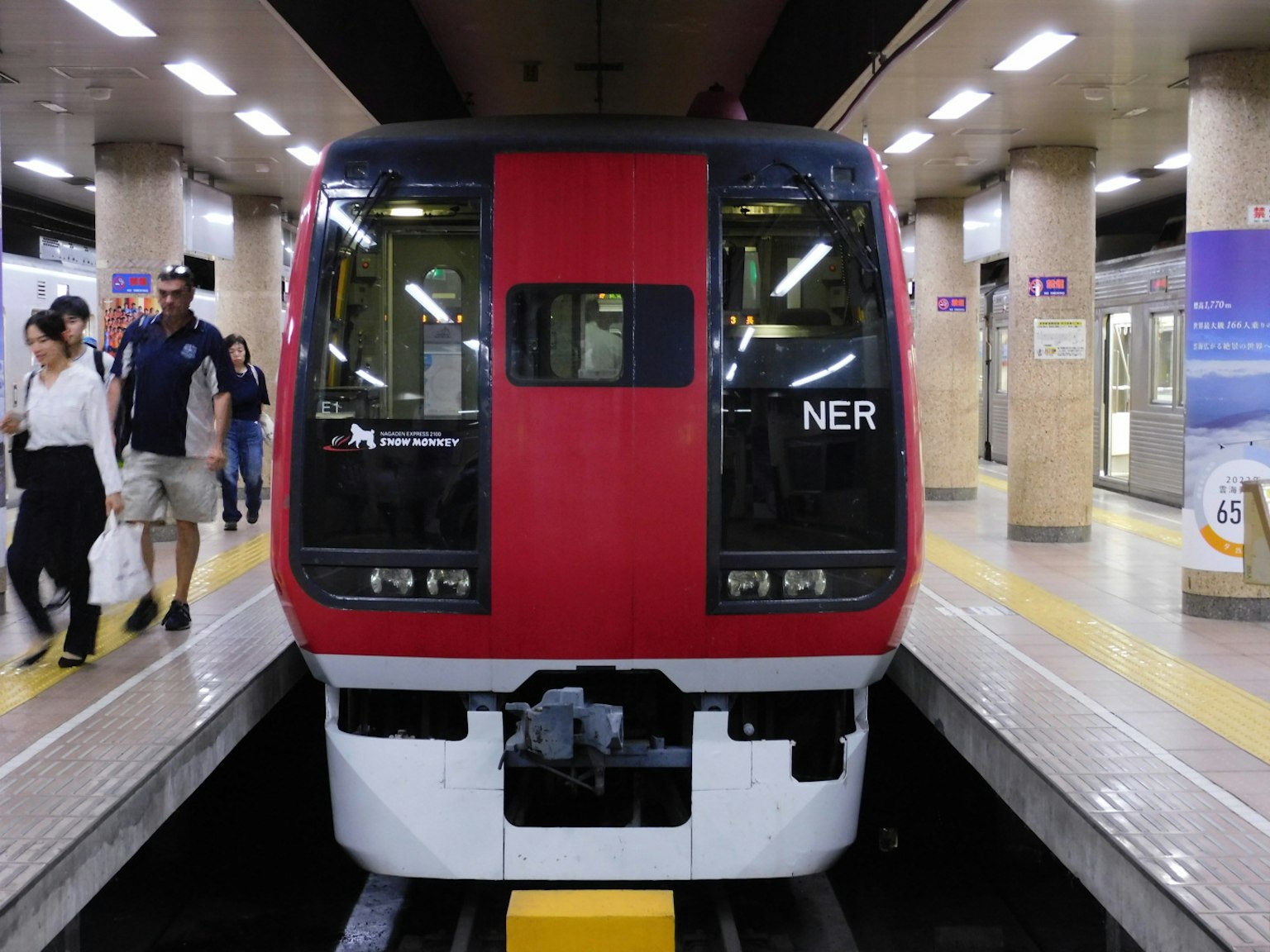 红色列车停在地铁站，有乘客上下车
