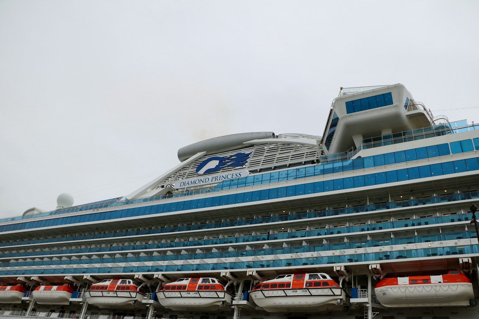 Cruise ship with blue stripes and lifeboats visible
