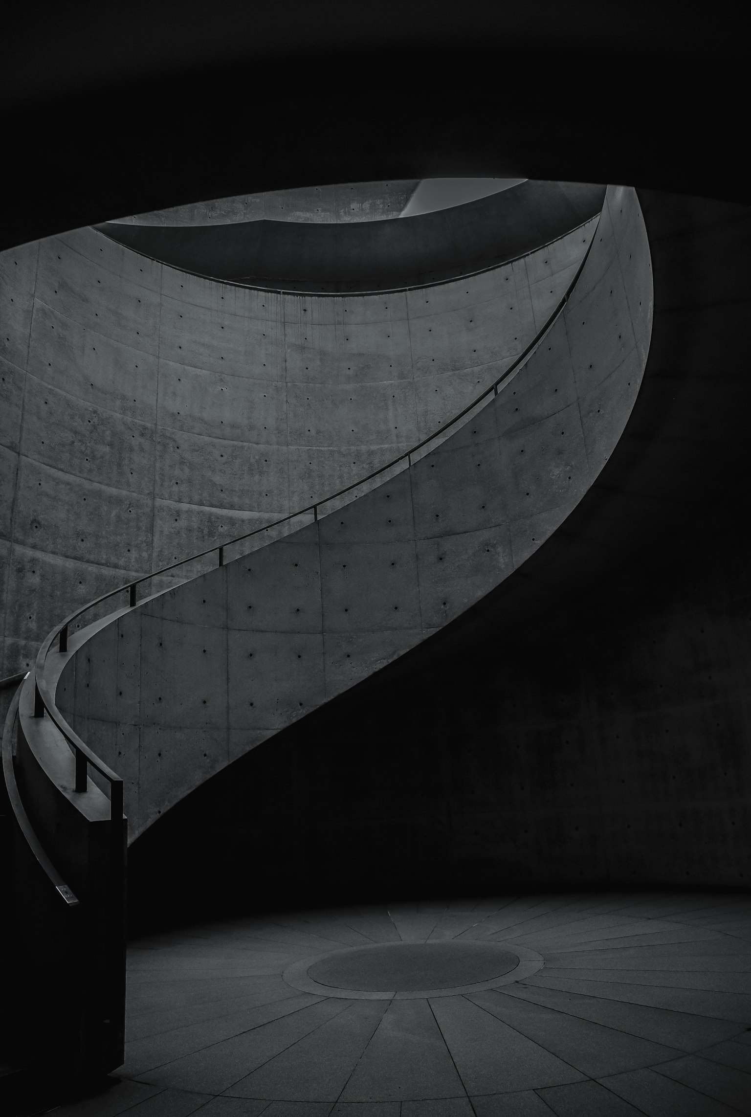 Scala in cemento curvo in uno spazio scuro